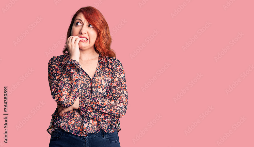 Young beautiful redhead woman wearing casual t-shirt looking stressed and nervous with hands on mouth biting nails. anxiety problem. Young beautiful redhead woman wearing casual t-shirt looking stressed and nervous with hands on mouth biting nails. anxiety problem.