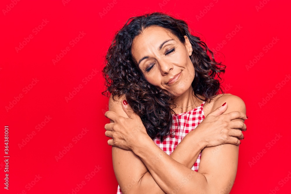 Middle age beautiful woman wearing casual sleeveless t shirt hugging oneself happy and positive, smiling confident. self love and self care