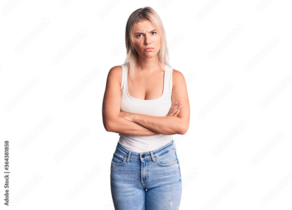 Young beautiful blonde woman wearing casual sleeveless t-shirt skeptic and nervous, disapproving expression on face with crossed arms. negative person. Young beautiful blonde woman wearing casual sleeveless t-shirt skeptic and nervous, disapproving expression on face with crossed arms. negative person.