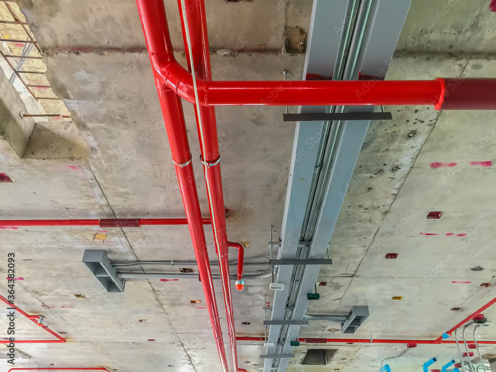 Red fire extinguisher pipe lines under construction on the ceiling