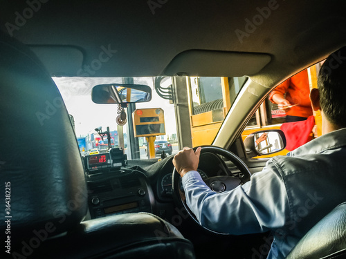 Taxi driver stop the car on express way, tollway or motorway gate booth for paying toll fee.