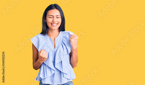 Young beautiful latin girl wearing casual clothes celebrating surprised and amazed for success with arms raised and eyes closed. winner concept. © Krakenimages.com