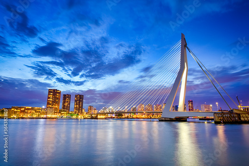 Netherlands Travel Destination. Night View of Renowned Erasmusbrug (Swan Bridge) in Rotterdam in Front of Port with Harbour. Shoot Made At Dusk.