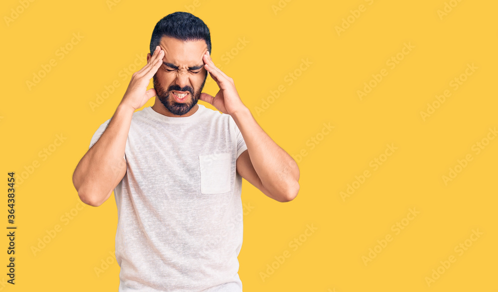 Young hispanic man wearing casual clothes with hand on head for pain in head because stress. suffering migraine. Young hispanic man wearing casual clothes with hand on head for pain in head because stress. suffering migraine.