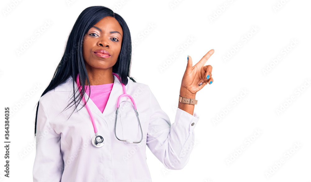 Young african american woman wearing doctor stethoscope pointing with hand finger to the side showing advertisement, serious and calm face Young african american woman wearing doctor stethoscope pointing with hand finger to the side showing advertisement, serious and calm face