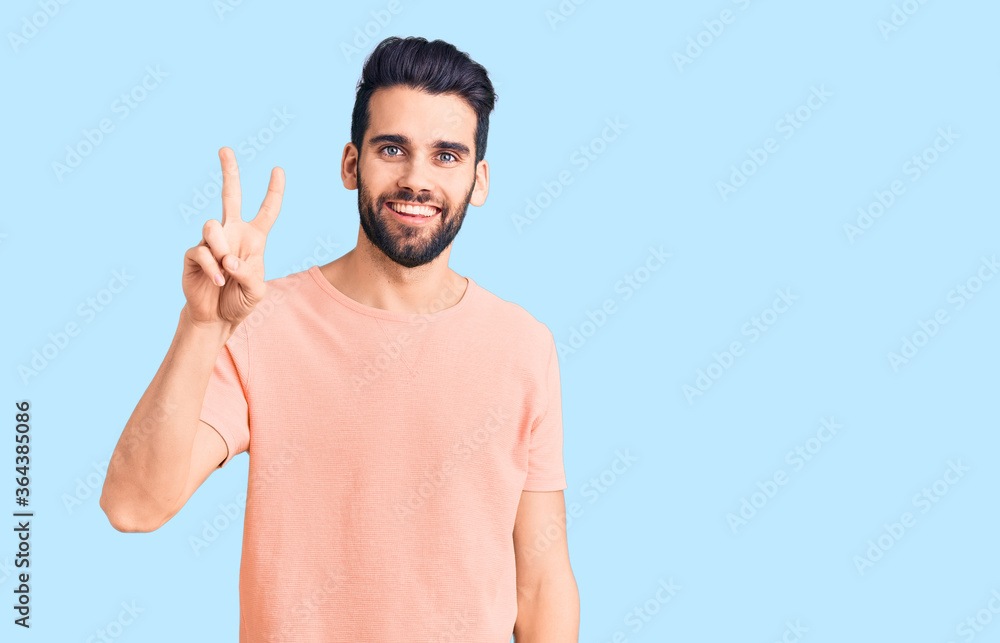 Young handsome man with beard wearing casual t-shirt showing and pointing up with fingers number two while smiling confident and happy. Young handsome man with beard wearing casual t-shirt showing and pointing up with fingers number two while smiling confident and happy.