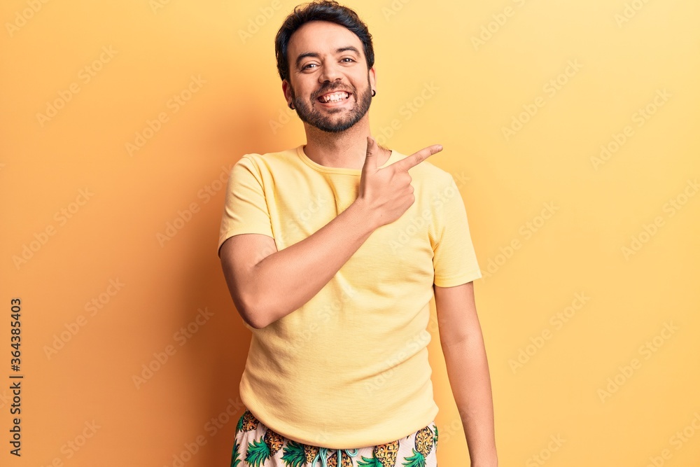 Young hispanic man wearing swimwear smiling cheerful pointing with hand and finger up to the side Young hispanic man wearing swimwear smiling cheerful pointing with hand and finger up to the side
