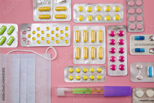 Different tablets and pills in blister packs, medications drugs on pinck background photo