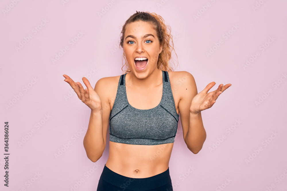 Young beautiful blonde sportswoman with blue eyes doing exercise wearing sportswear celebrating crazy and amazed for success with arms raised and open eyes screaming excited. Winner concept Young beautiful blonde sportswoman with blue eyes doing exercise wearing sportswear celebrating crazy and amazed for success with arms raised and open eyes screaming excited. Winner concept