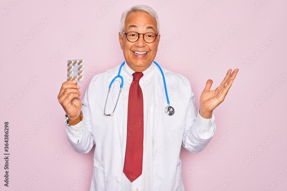 Middle age senior grey-haired doctor man holding prescription pills over pink background very happy and excited, winner expression celebrating victory screaming with big smile and raised hands Middle age senior grey-haired doctor man holding prescription pills over pink background very happy and excited, winner expression celebrating victory screaming with big smile and raised hands