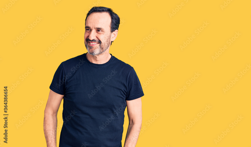 Middle age handsome man wearing casual t-shirt looking away to side with smile on face, natural expression. laughing confident. Middle age handsome man wearing casual t-shirt looking away to side with smile on face, natural expression. laughing confident.
