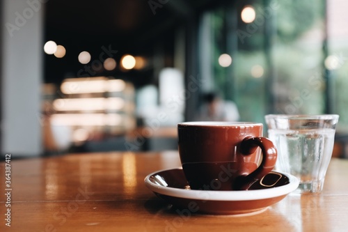Close up view of a brown coffee cup on a wooden table in a coffee shop