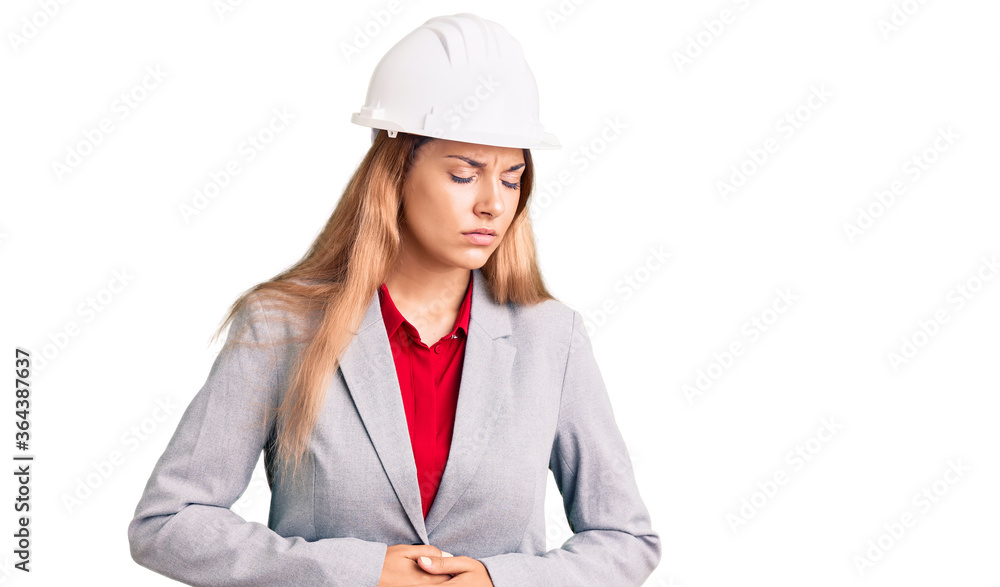 Beautiful young woman wearing architect hardhat with hand on stomach because indigestion, painful illness feeling unwell. ache concept. Beautiful young woman wearing architect hardhat with hand on stomach because indigestion, painful illness feeling unwell. ache concept.