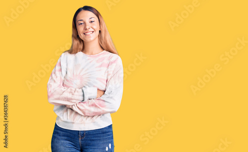 Beautiful young woman wearing casual tie dye sweatshirt happy face smiling with crossed arms looking at the camera. positive person.