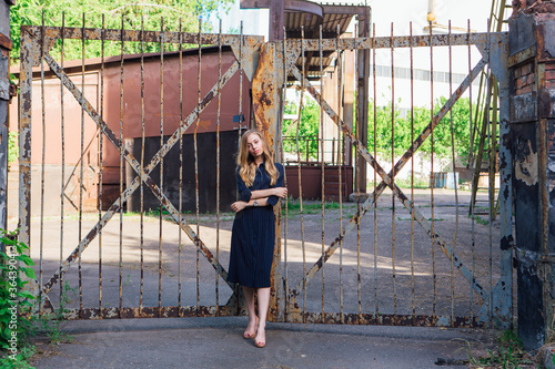 Fashion look's woman near the old rusty gate. Young woman modern portrait.
