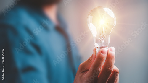 Idea innovation and inspiration concept.Hand of man holding illuminated light bulb, concept creativity with bulbs that shine glitter.Inspiration of ideas for sustainable business development.