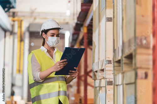 Asian woman hold flip chart wear face mask as new normal in warehouse 