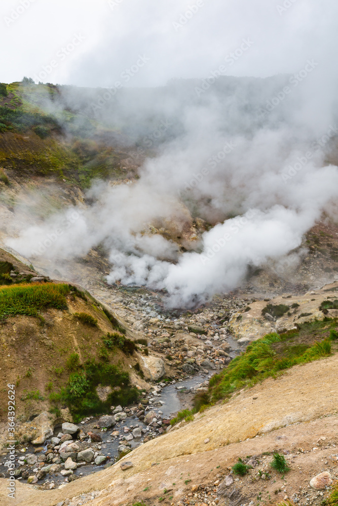 Exciting view of volcanic landscape, eruption fumarole, aggressive hot spring, gas-steam activity in crater of active volcano. Beautiful mountain landscape, travel destinations for active vacation.