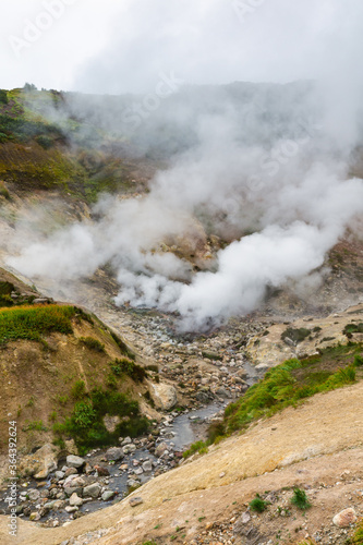 Exciting view of volcanic landscape, eruption fumarole, aggressive hot spring, gas-steam activity in crater of active volcano. Beautiful mountain landscape, travel destinations for active vacation.