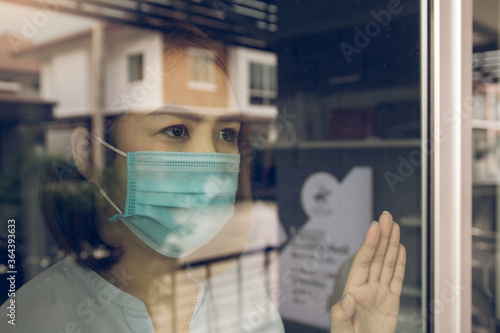 Tableau sur toile Asian woman looking through the window and wearing medical mask protection from the illness with stay isolated quarantine COVID-19 pandemic virus mask against coronavirus disease at home