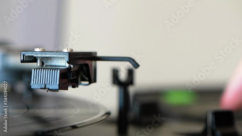 Vinyl record player spinning on vintage vinyl turntable player and being stopped by a woman hand. photo