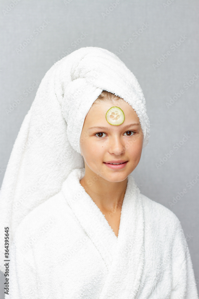 Obraz premium Little girl face with cucumber mask and with towel on the head