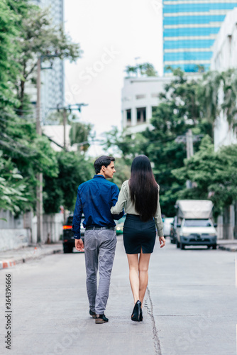 Romantic moments. Full length shot of beautiful well dressed couple, going for a walk outdoors. Love, relationship, dating concept. Rear view. Vertical shot