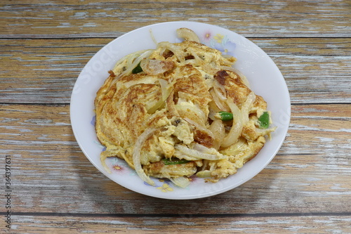 Spicy Fried chicken egg (Omelette egg) with sliced fresh onion and chilly on the plate. Famous street food in Asia. Comfortable food with cheap price in Thailand. 