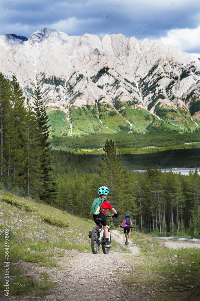 Kids ride their mountain bikes down a hill while riding the High Rockies Trail in Kananaskis Alberta.