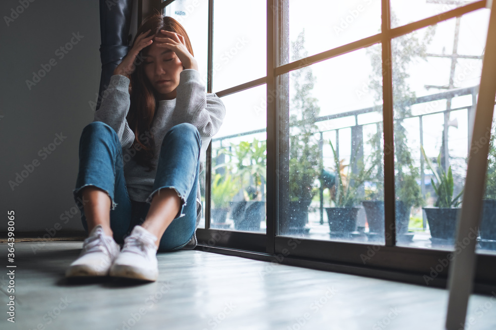 A sad and stressed young asian woman sitting alone in the room A sad and stressed young asian woman sitting alone in the room