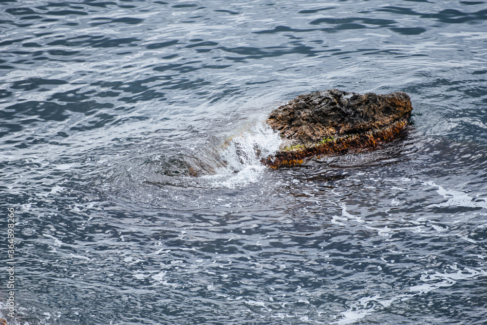 A picturesque lonely large stone stands on all sides surrounded by water. A picturesque lonely large stone stands on all sides surrounded by water.