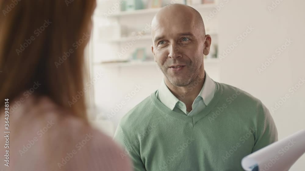 Over-the-shoulder slow motion shot of handsome mature businessman discussing some financial issues of new agreement with colleague sitting in front of himOver-the-shoulder slow motion shot of handsome Over-the-shoulder slow motion shot of handsome mature businessman discussing some financial issues of new agreement with colleague sitting in front of himOver-the-shoulder slow motion shot of handsome