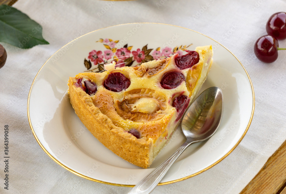Piece of fruit cake with sour cream filling, apricots and cherries on a white plate Piece of fruit cake with sour cream filling, apricots and cherries on a white plate