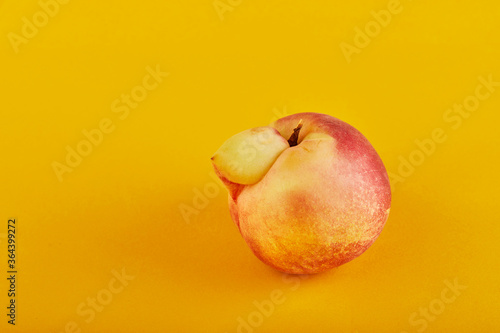An ugly fruit or vegetable. Very ugly peach mutant on an orange background. Ugly fruits are not in high demand
