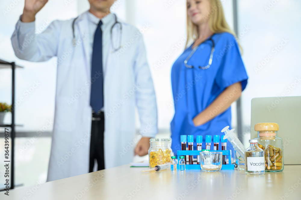 Fototapeta premium Lab equipment with liquid inside stand on the table with doctors wearing formal white coat and blue scrubs suit at the background.
