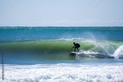 Japan surfing , sometimes during a typhoon, there are many waves in Japan especially in Hebara, Katsuura, Chiba. Westerner surfs large waves. Sunrise & at the beach with a surfer & his surf board.