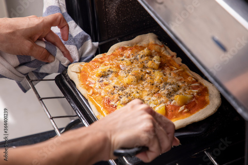 woman's hands taking pizza out of the oven