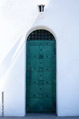 beautiful old door, white walls, the rays of the sun fall on the walls.  © Nastia