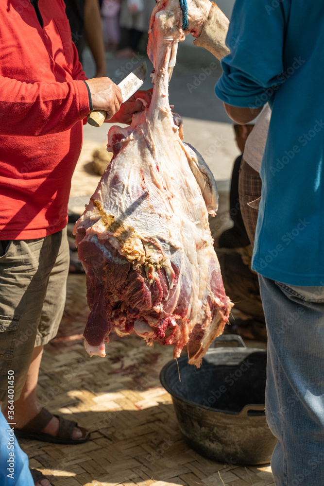 Adult men hold knives to skin the legs of cows that are hung during the Eid al-Adha celebration together