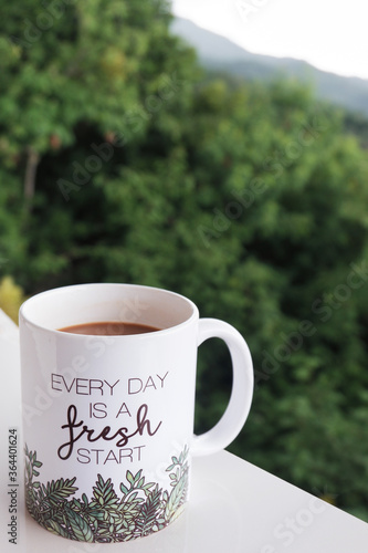 Coffee mug with inspirational message with nature background. Every day is a fresh start. Copy space.