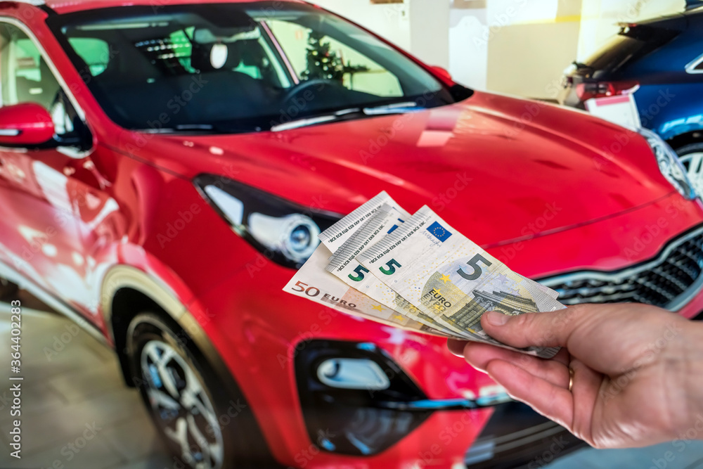 concept of buying a new car. male hand holds a euro for a successful deal