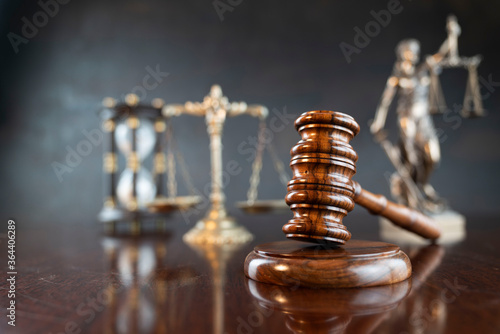 Law symbols composition. Themis statue, judge’s gavel and scale of justice on shining brown table and gray background. photo