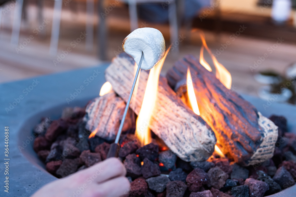 Roasting marshmallow over a gas fire while glamping Stock Photo Adobe