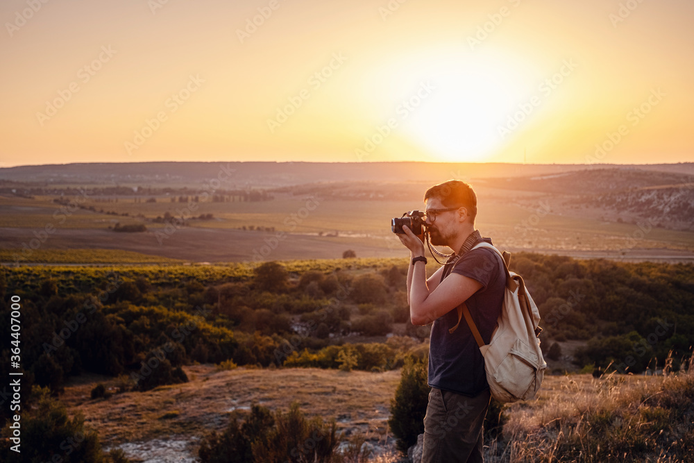Man photographer with backpack and camera taking photo of sunset mountains Man photographer with backpack and camera taking photo of sunset mountains