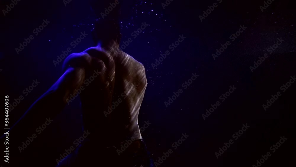 muscular sexy man with naked torso is moving underwater, silhouette in darkness muscular sexy man with naked torso is moving underwater, silhouette in darkness
