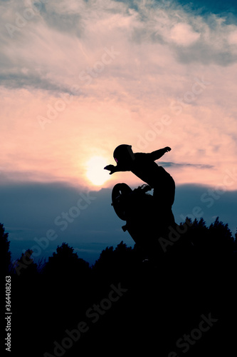 The silhouette of a motorcyclist at sunset. Moto rider making a stunt on his motorbike.