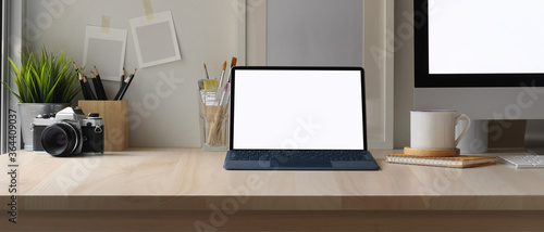 Simple worktable with mock up tablet, computer, camera, painting brushes, stationery and decorations in home office