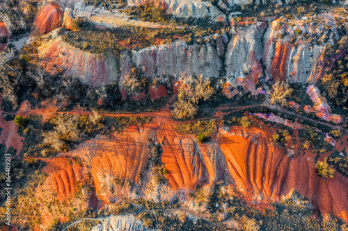 Gant, Hungary - Aerial horizontal drone view of abandoned bauxite mine with warm red and orange colors and trees at sunset. Red bauxite texture
