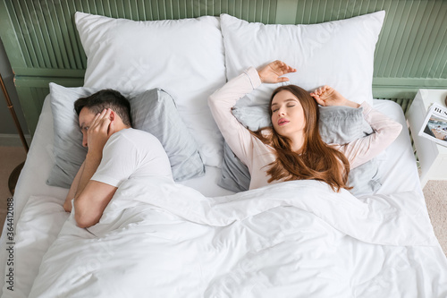 Young irritated man in bed ...