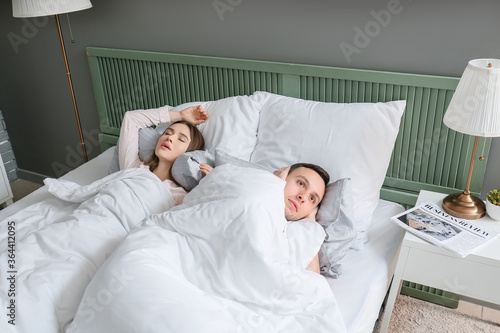 Young irritated man in bed ...